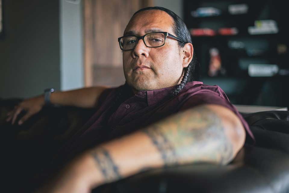 A photograph of Oscar Hokeah sitting in a chair looking at the viewer